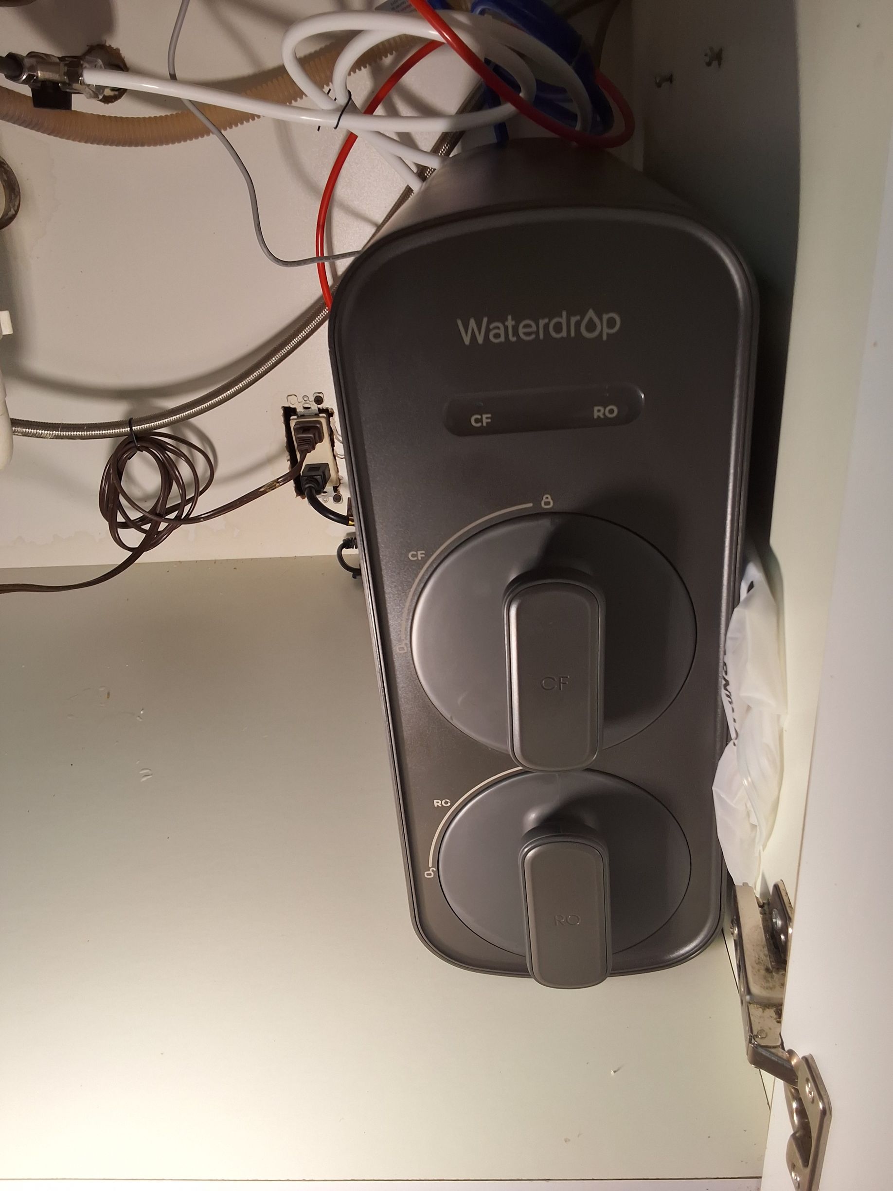 Black WeatherPro wall control with two dials, mounted under tangled wires in a utility space