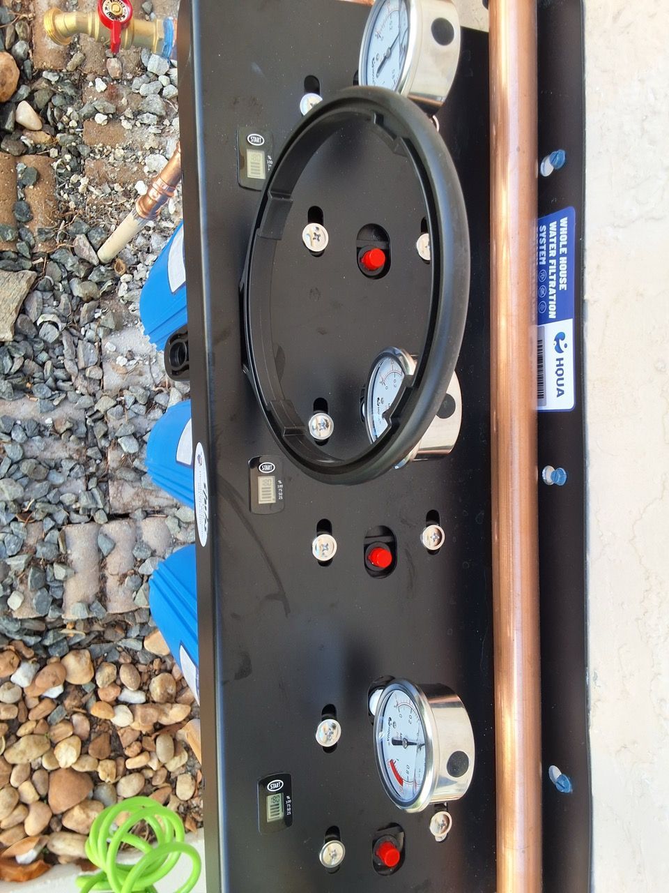Black control panel with dials and red buttons on gravel beside a blue train
