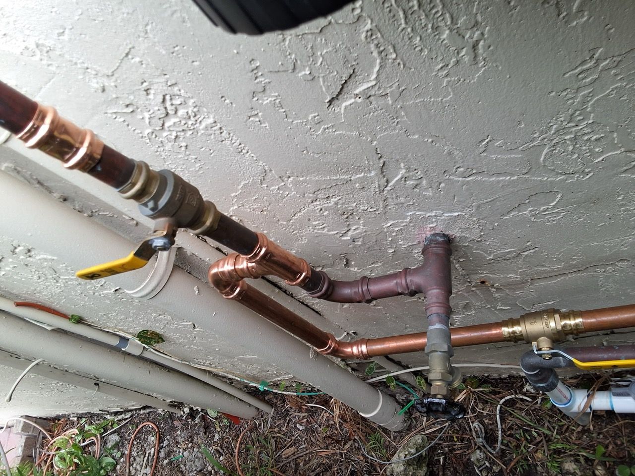 Ceiling with exposed copper and gray pipes running across a rough stucco surface.