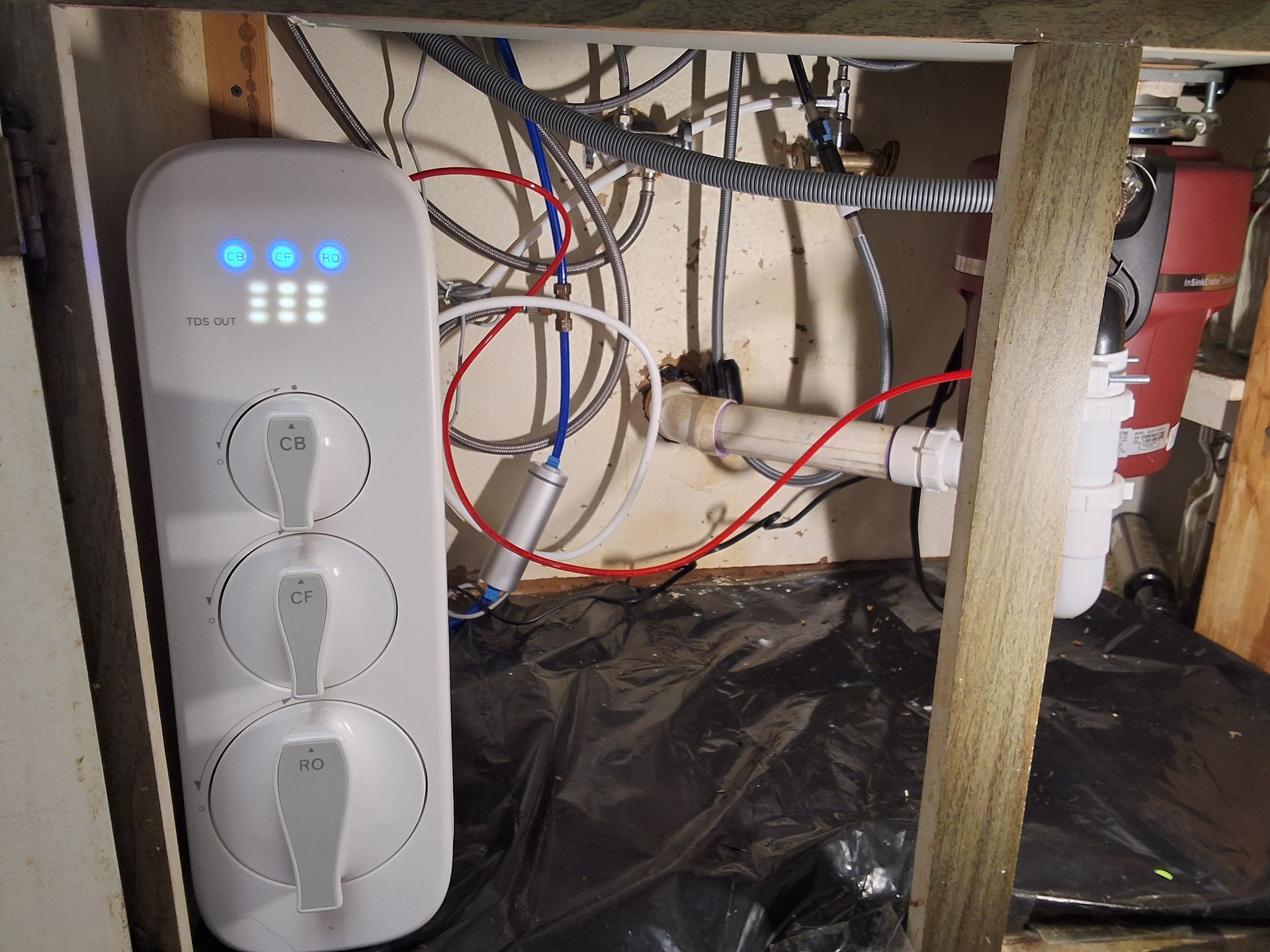 Open electrical cabinet with wiring, outlets, and blue indicator lights under a floor or crawlspace.