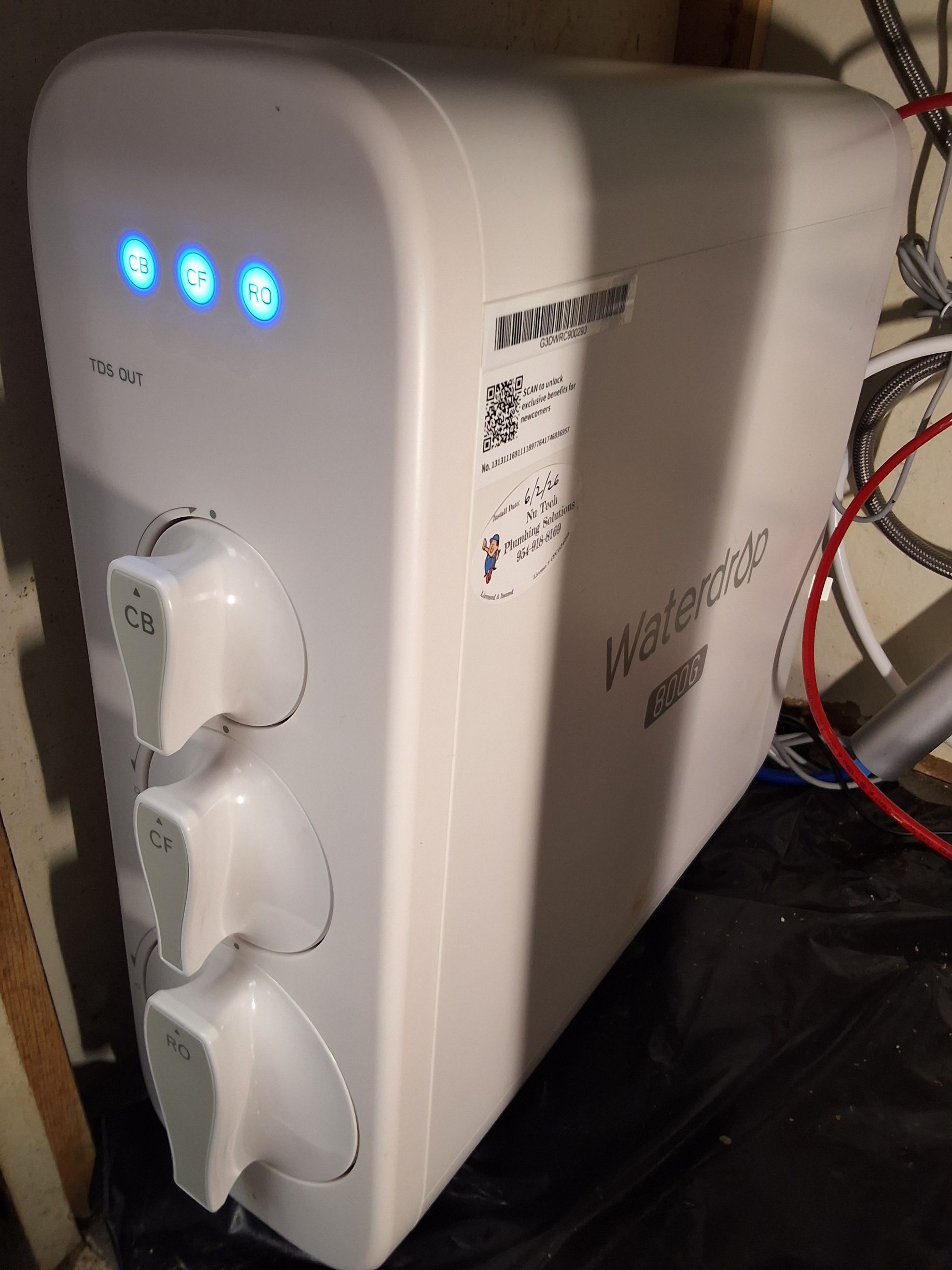 White countertop appliance with three blue indicator lights and two front dials, on a workbench.