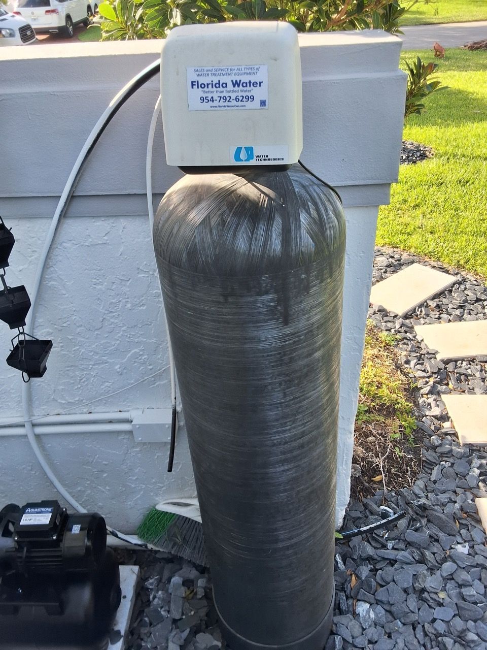 Outdoor water treatment tank wrapped in silver insulation beside a wall and lawn