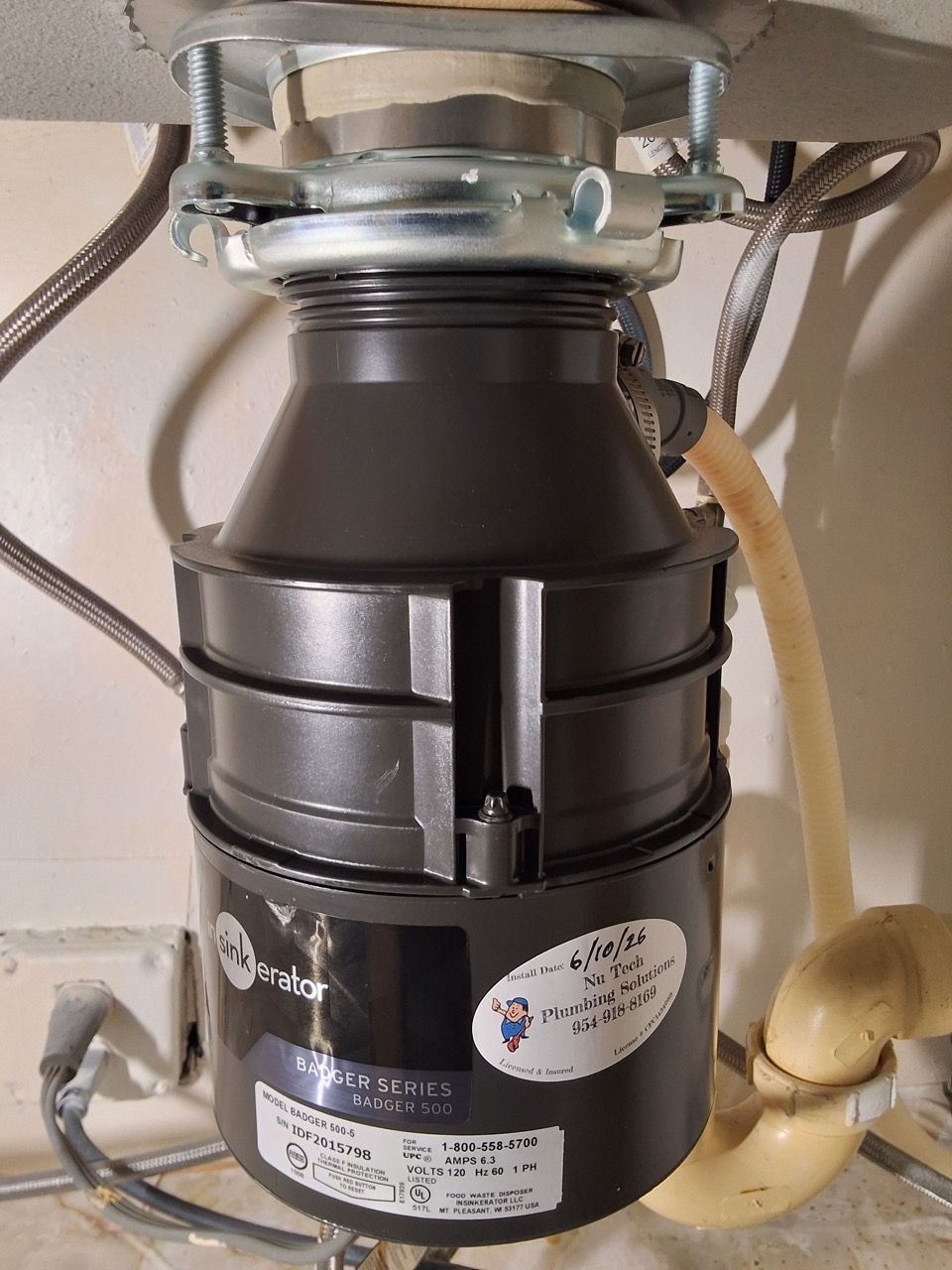 Under-sink garbage disposal unit with gray pipes and a beige drain hose