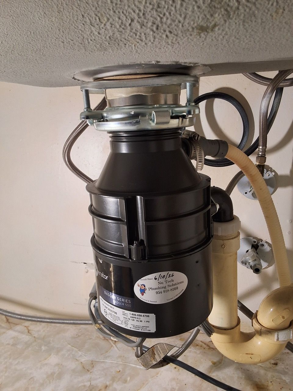 Under-sink garbage disposal with drain pipes and wiring underneath a countertop