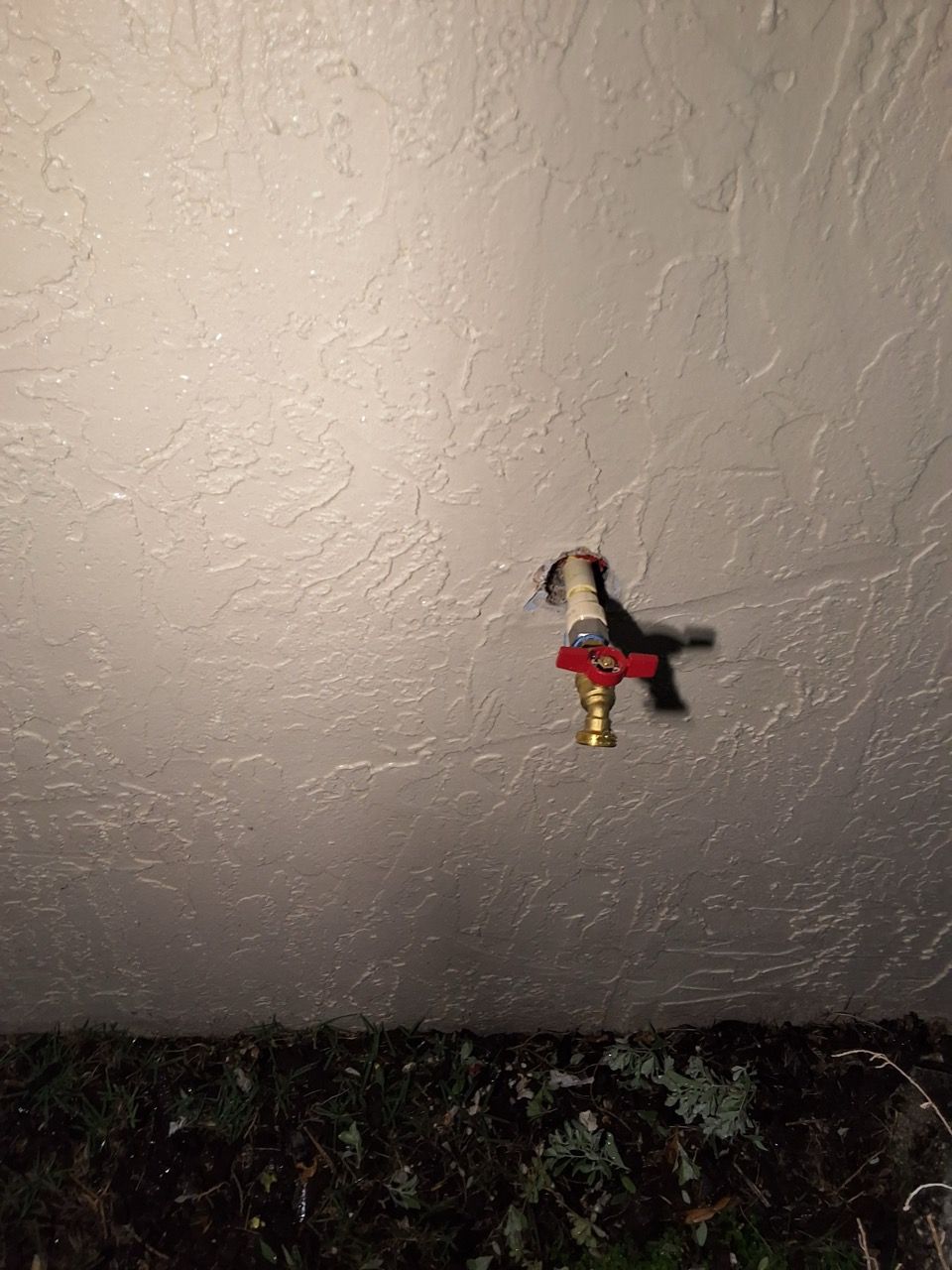 Small figurine hanging on a textured wall above a dark ledge.