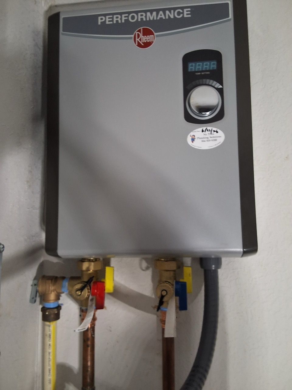 Performance water heater with pipes and hoses mounted on a wall.
