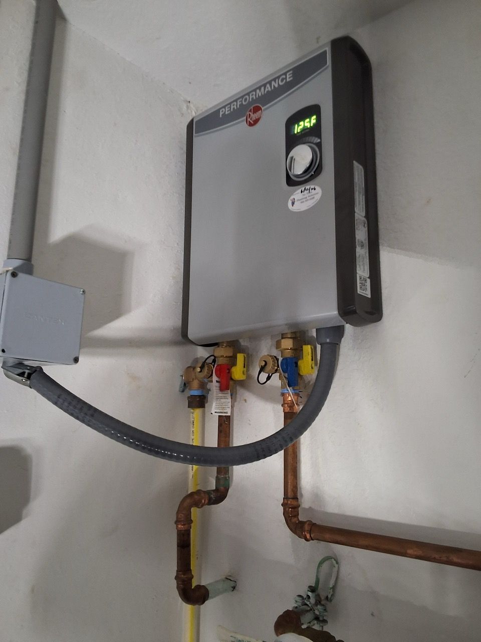 Wall-mounted gray water heater with pipes and control panel in a utility room