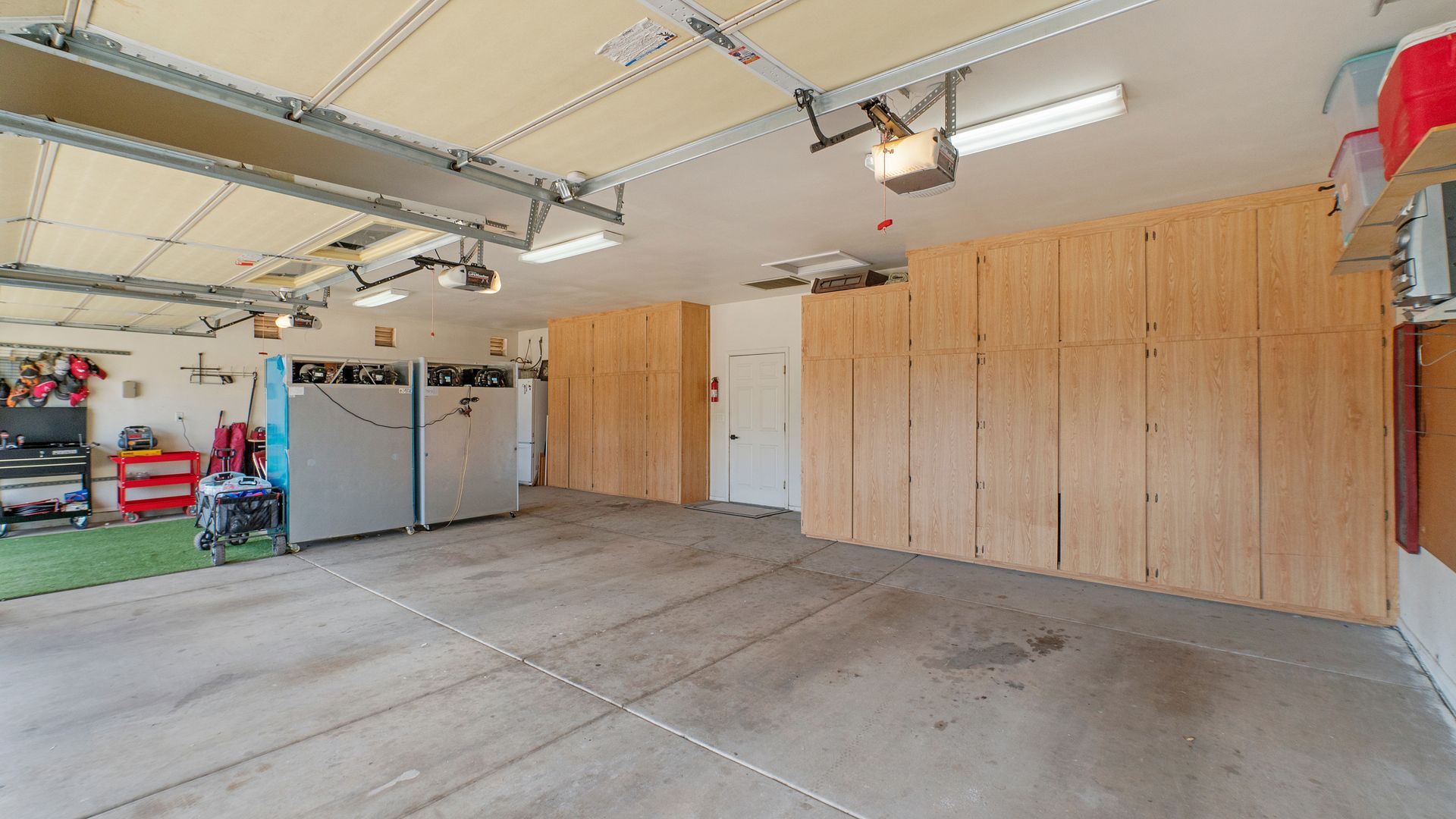 Spacious garage with concrete floor, wood-paneled storage walls, and overhead shelving.