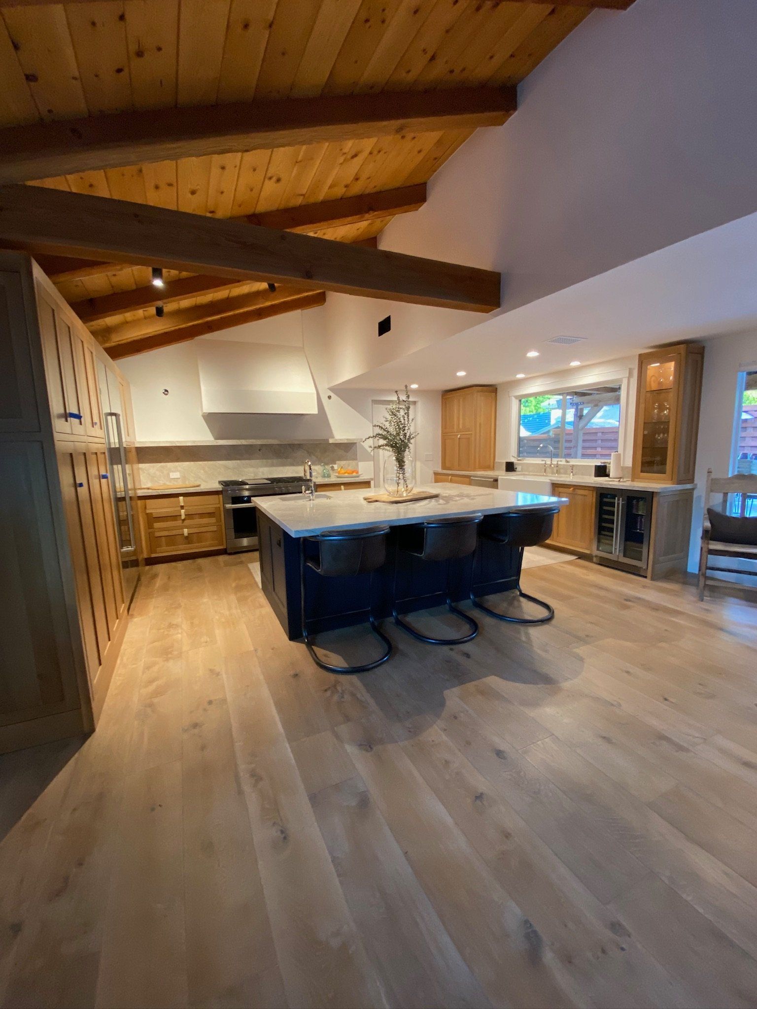 Modern kitchen with wood ceiling, island seating, and light hardwood floors