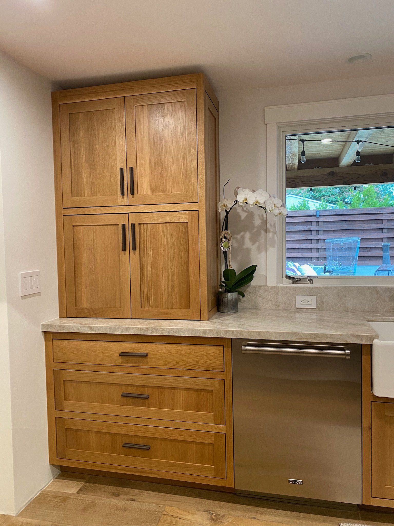 Kitchen with wood cabinets, granite countertop, stainless dishwasher, and a window above the sink area
