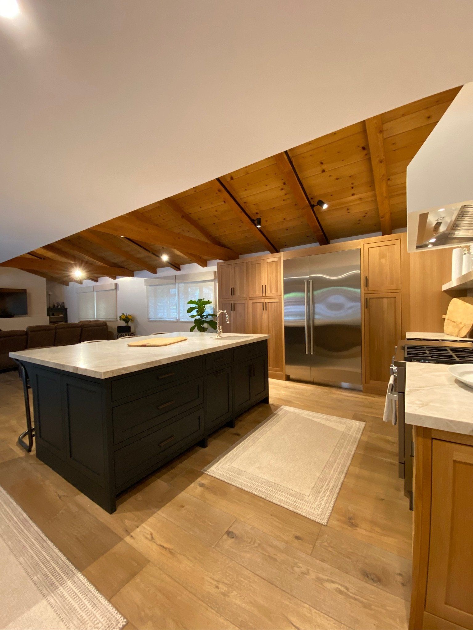 Modern kitchen with a large black island, wood ceiling, and stainless-steel appliances