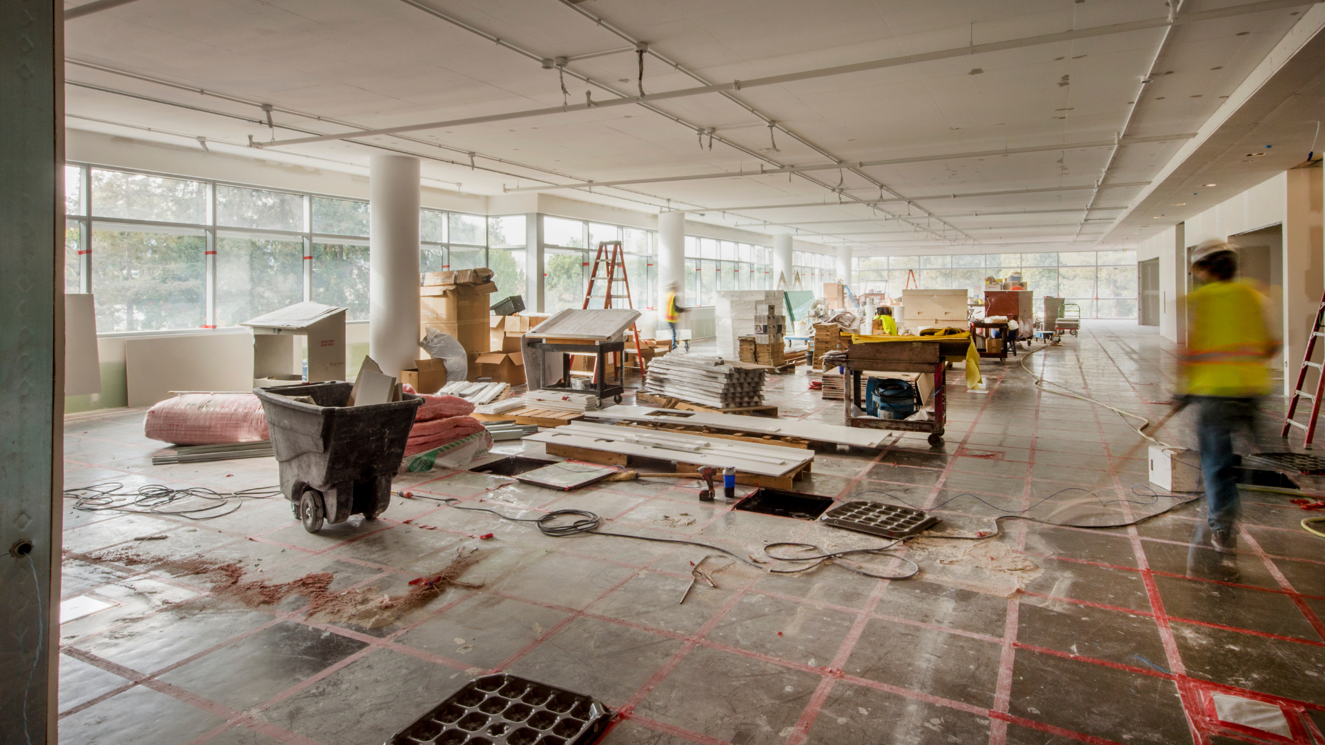 A large room is being remodeled and a man is walking through it.