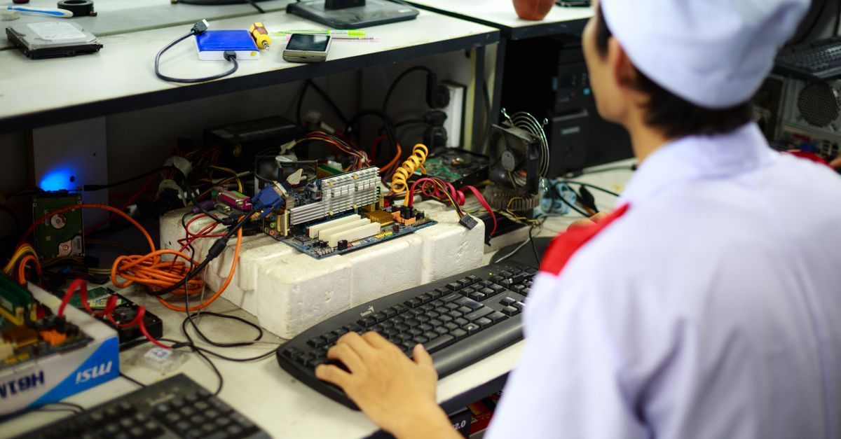 Persona sentada en un escritorio trabajando en equipos electrónicos y cables en un laboratorio o taller.