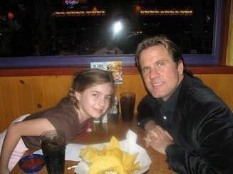 A man and a little girl are sitting at a table in a restaurant.