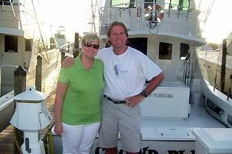 A man and a woman are posing for a picture in front of a boat.