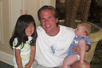 A man is holding a baby and a little girl.