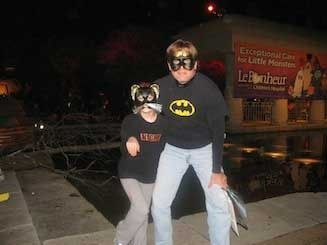 A man and a boy wearing batman masks are standing next to each other.