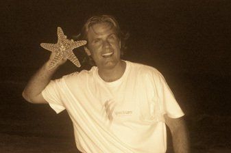 A man in a white shirt is holding a starfish over his head