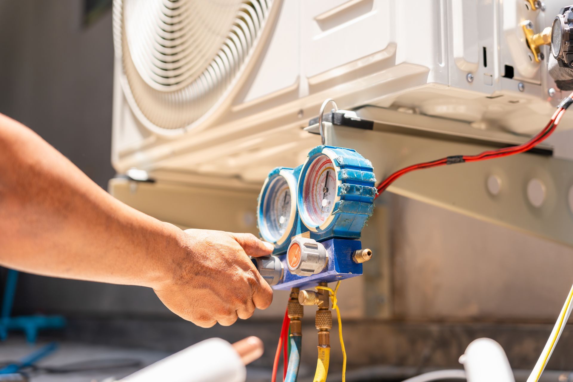 Technician checks an air conditioner’s refrigerant pressure using a manifold gauge.