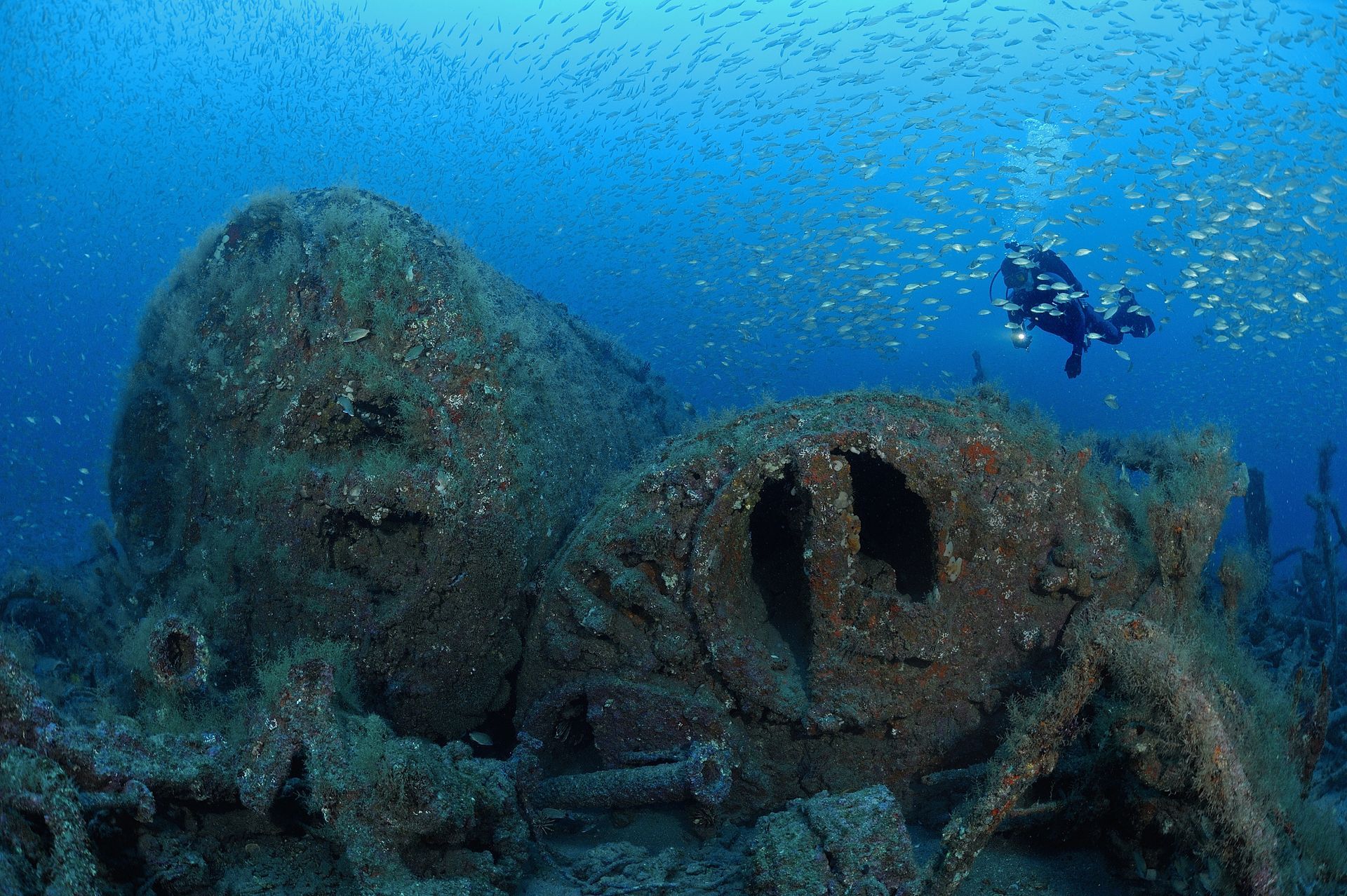A group of scuba divers are swimming in the ocean near a large rock.