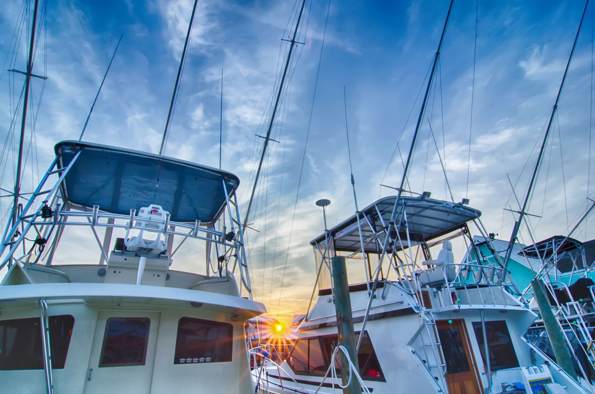 A group of boats are docked in a marina at sunset.