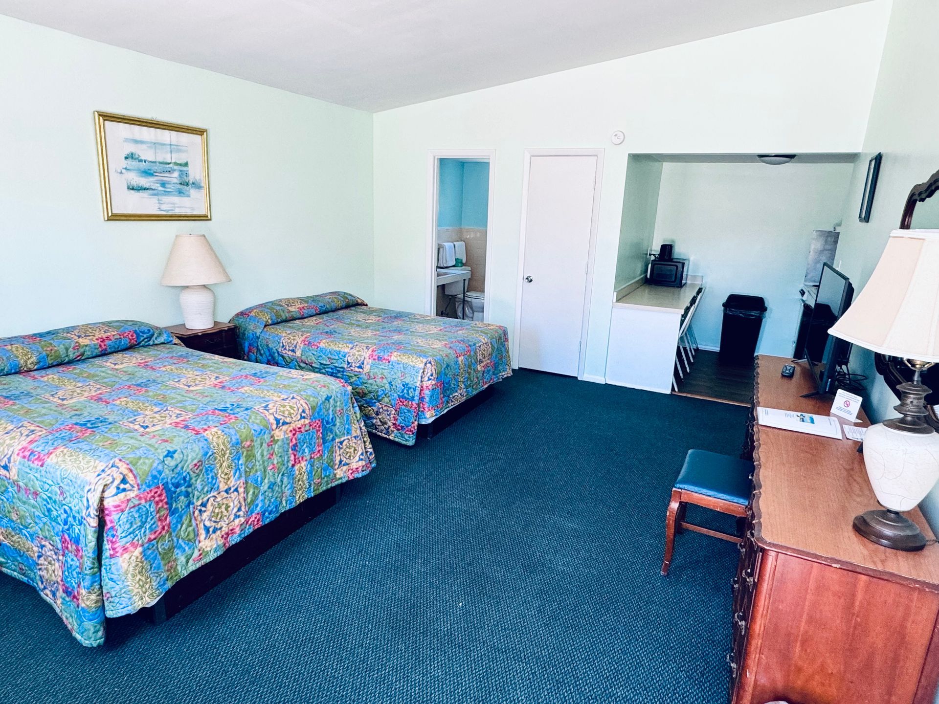 A hotel room with two beds , a desk and a lamp.