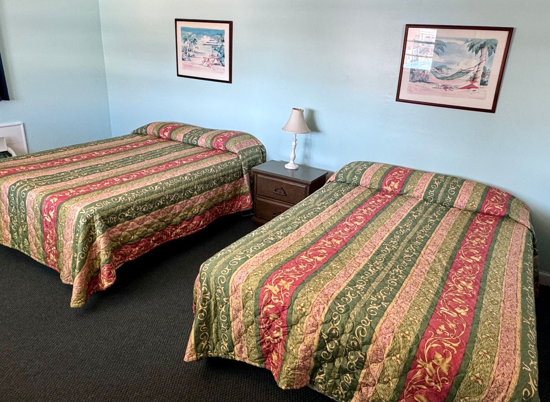A hotel room with two beds and two pictures on the wall.