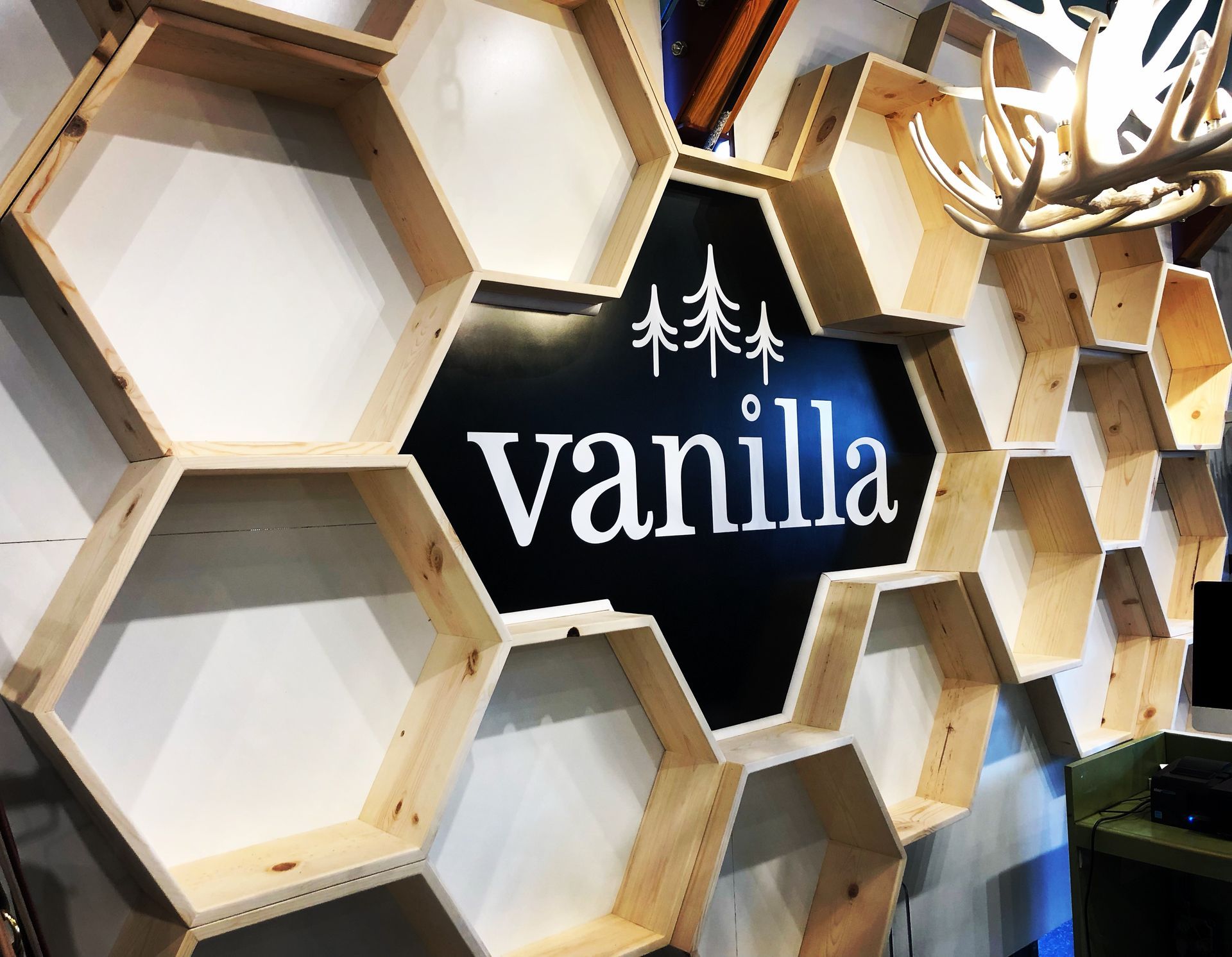 A wooden, honeycomb-style display shelving unit featuring a central black sign with the word 