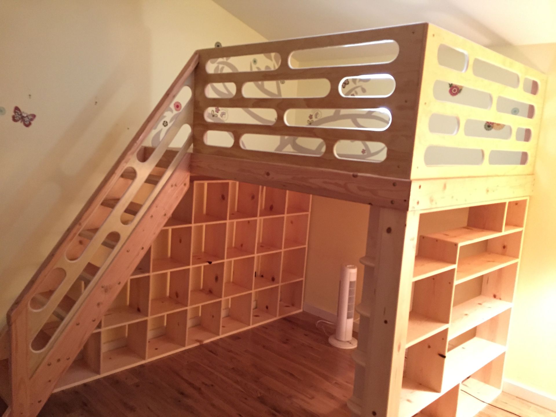 Wooden loft bed with a built-in staircase featuring open cubby storage underneath and attached side shelving.