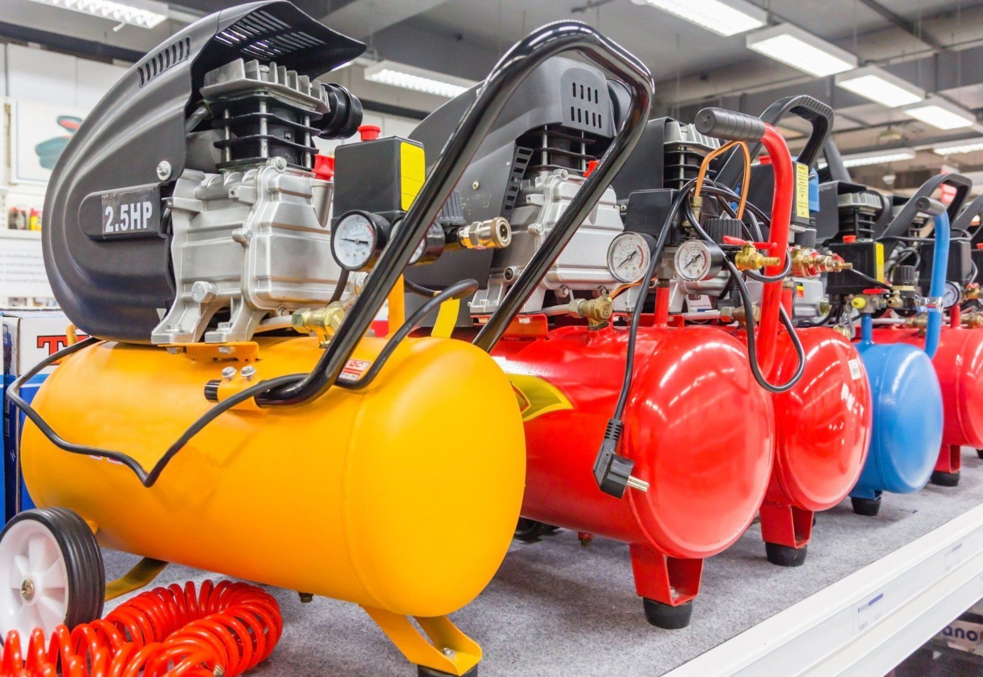Una fila di compressori d'aria sono allineati su uno scaffale in un negozio.