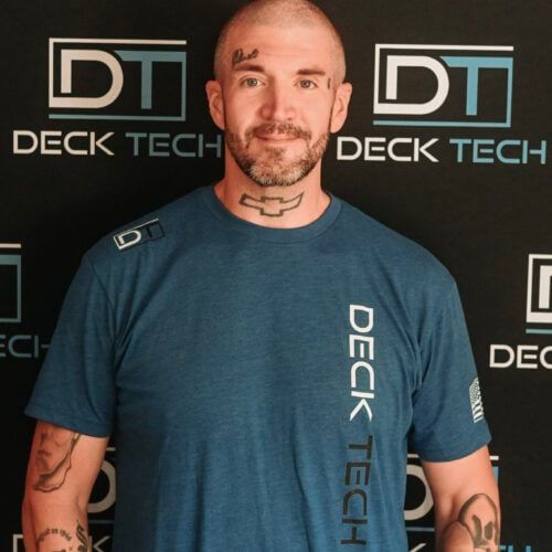 Man with tattoos and shaved head wearing a blue