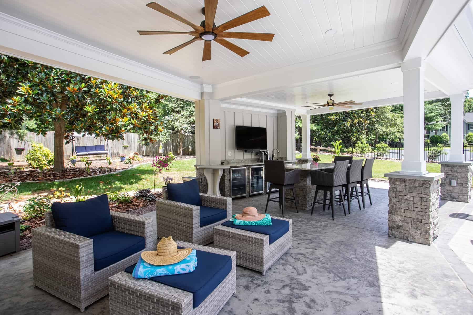 Outdoor patio with seating, bar, and TV under a covered area.