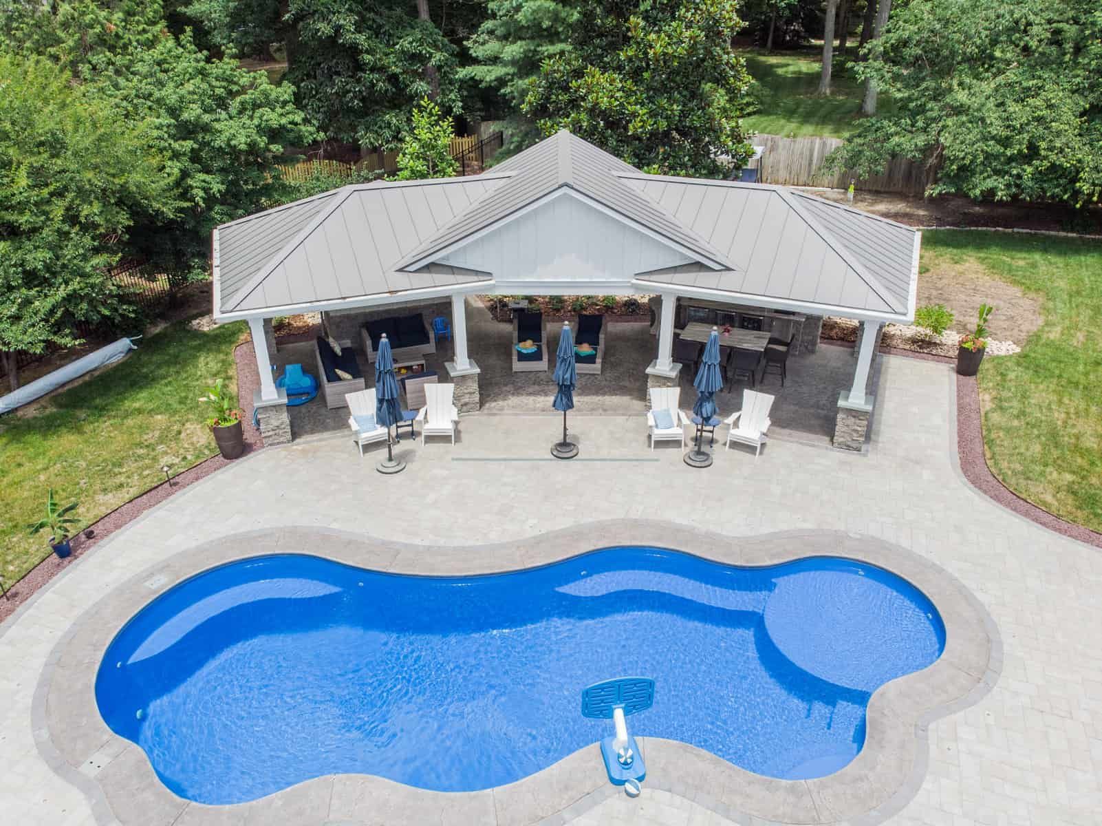 Overhead view of a swimming pool with a gazebo, patio furniture, and surrounding greenery.