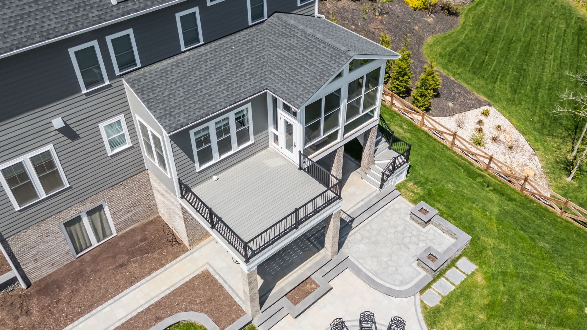 Overhead view of a pergola-covered patio with geometric tile design and surrounding brick buildings and trees.