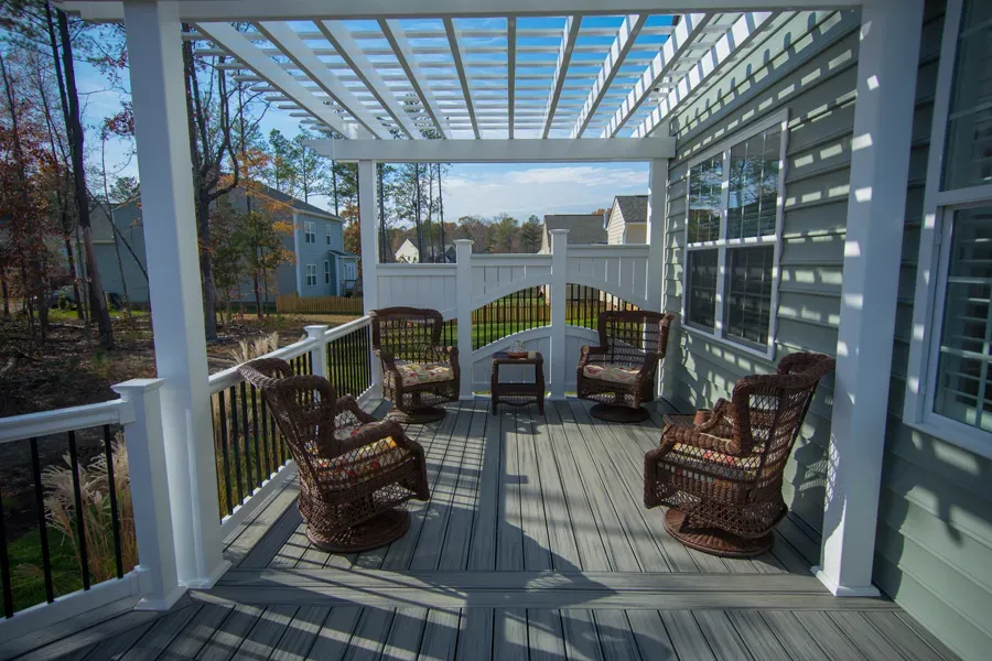 Covered outdoor porch with wicker furniture and pergola.