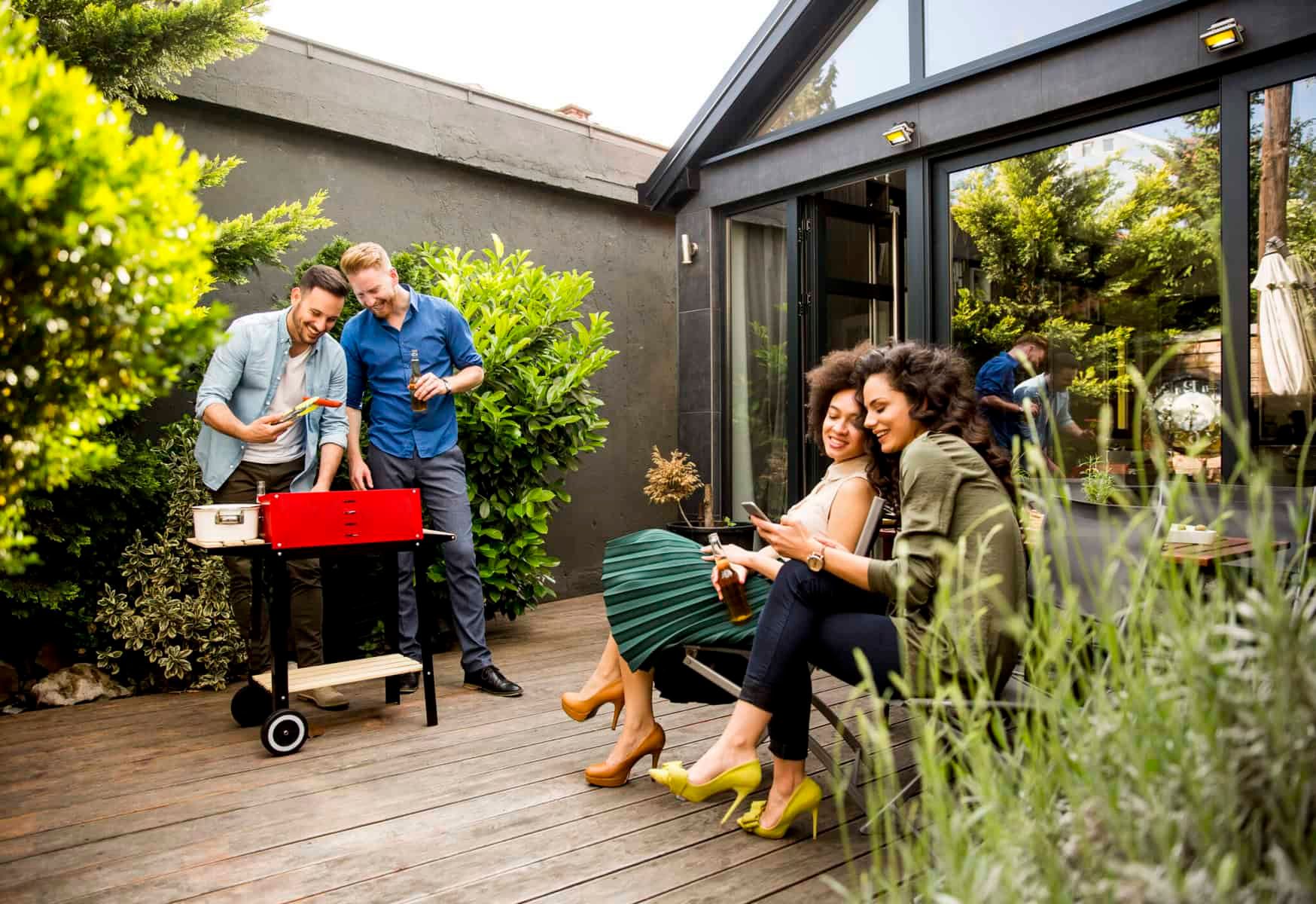 Group of friends barbecuing and relaxing outdoors on a sunny day.
