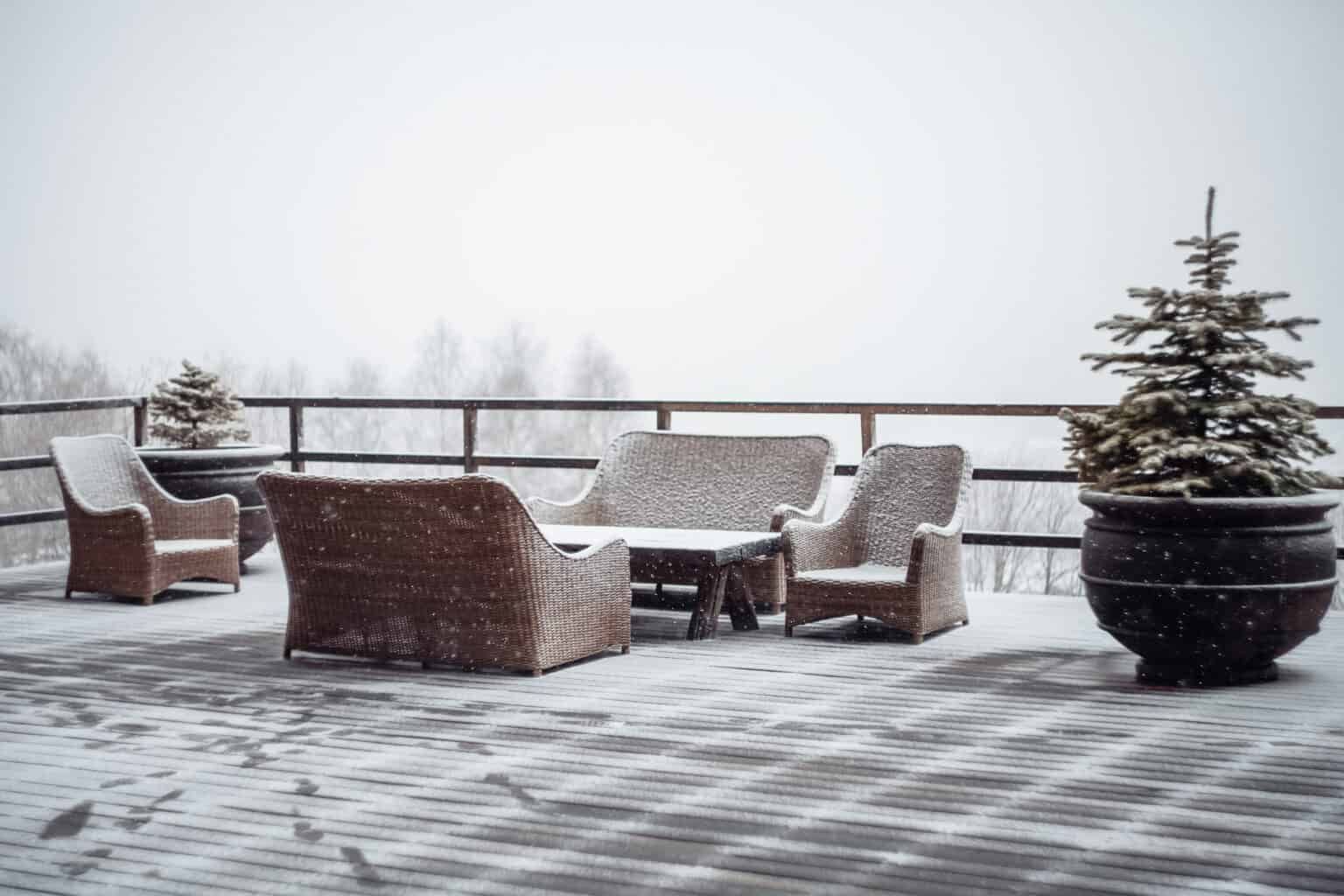 Snow-covered outdoor patio furniture, evergreen trees, and snowy landscape.