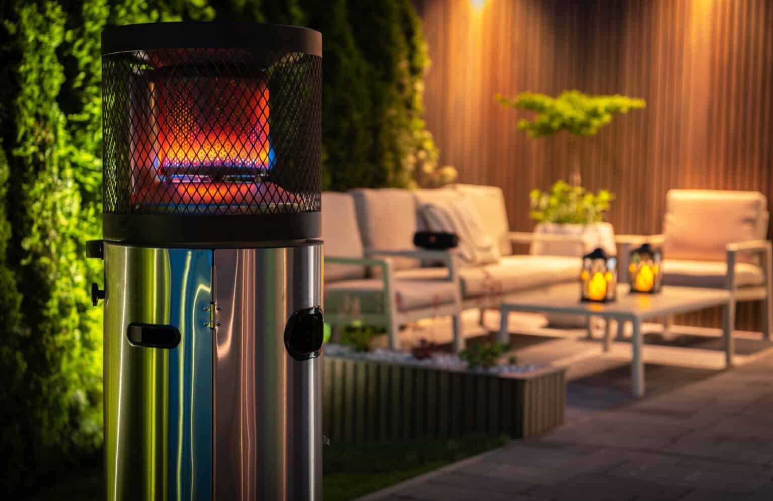 Outdoor propane patio heater with flames, near a seating area at night.