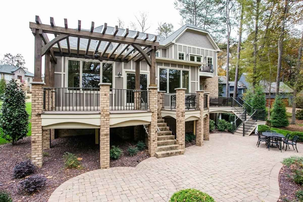 Back deck of a two-story house with pergola, brick columns, stairs, and patio.