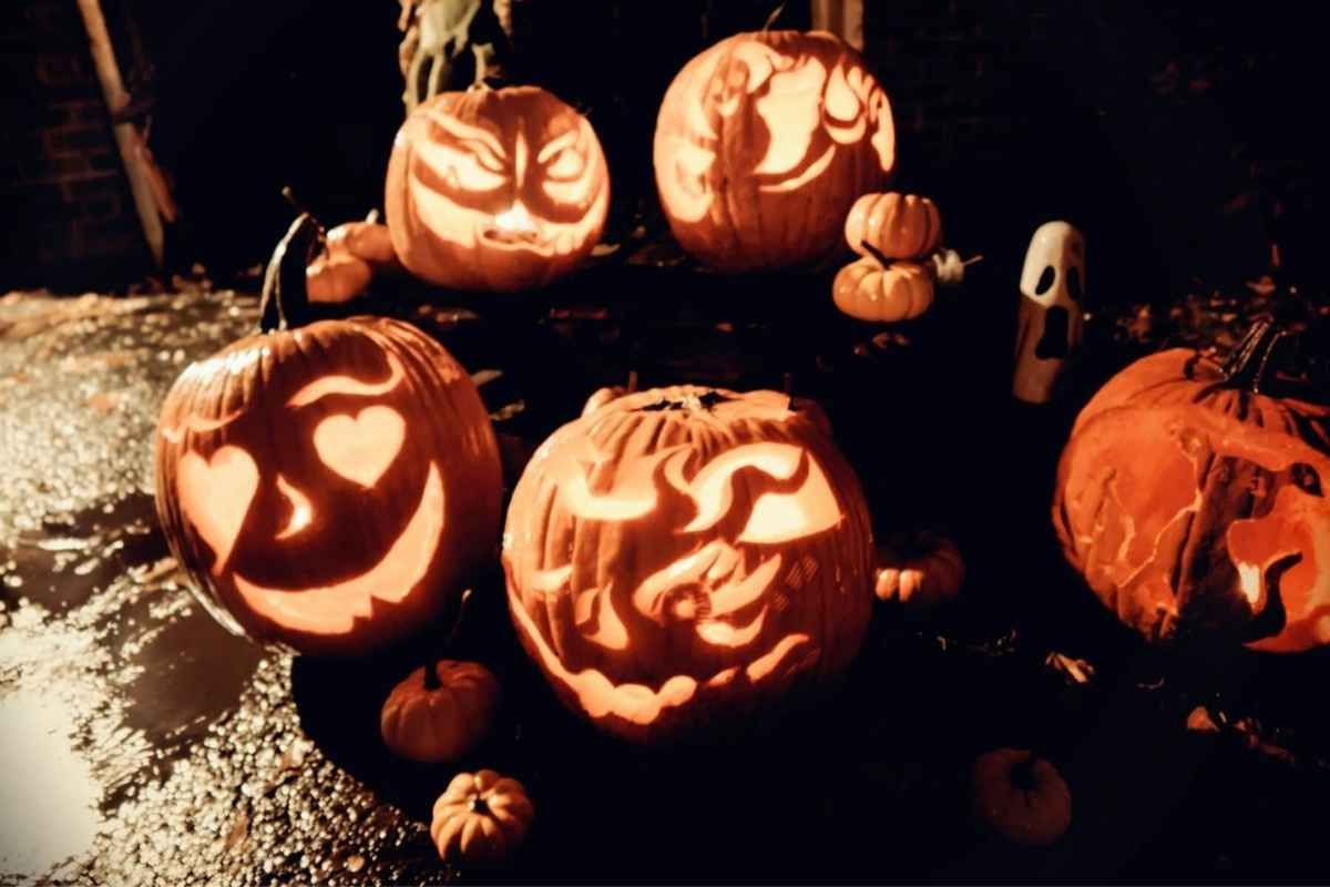 Glowing carved pumpkins with various faces, lit at night for Halloween.