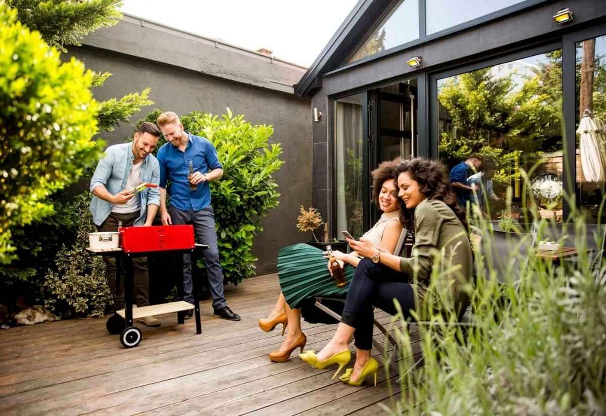 Group of friends barbecuing and relaxing outdoors on a sunny day.