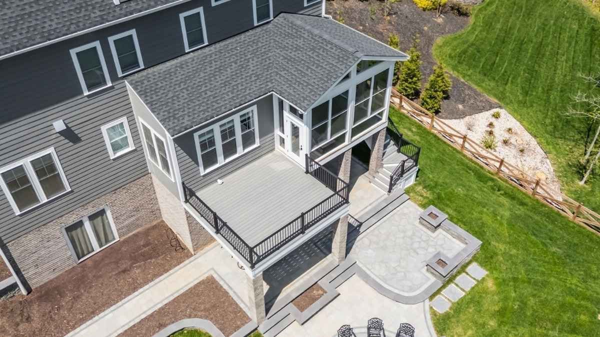 Overhead view of a pergola-covered patio with geometric tile design and surrounding brick buildings and trees.