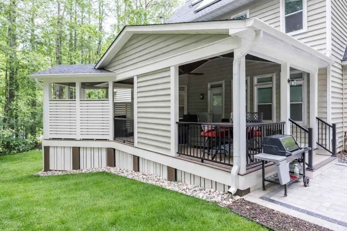 Outdoor deck with a hot tub, seating area, pergola, and built-in kitchen at dusk.