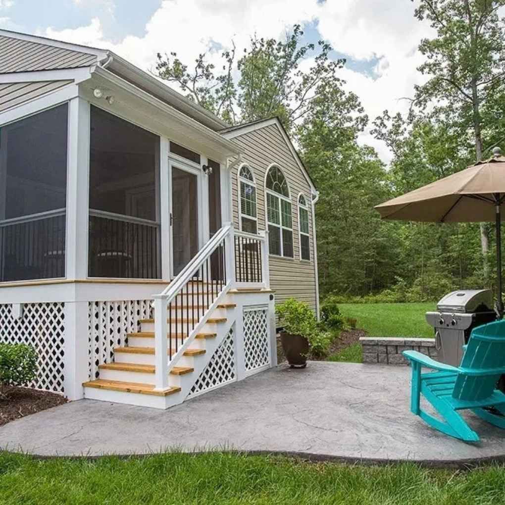 Backyard patio with screened porch, stairs, concrete, grill, turquoise chairs, and umbrella.