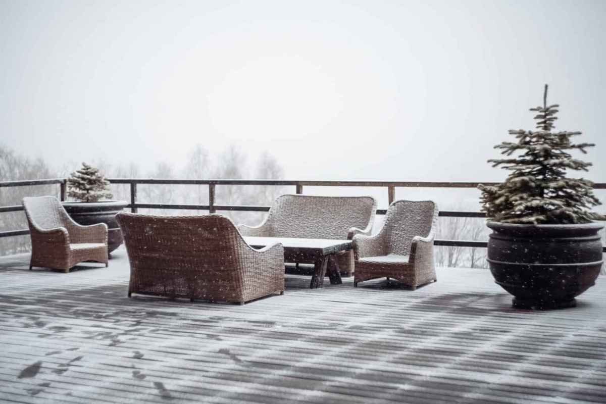 Snow-covered outdoor patio furniture, evergreen trees, and snowy landscape.