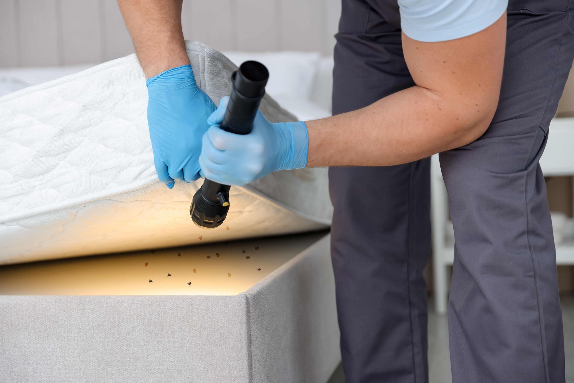 Gloved worker lifting a white membrane on a concrete structure with a black torch tool