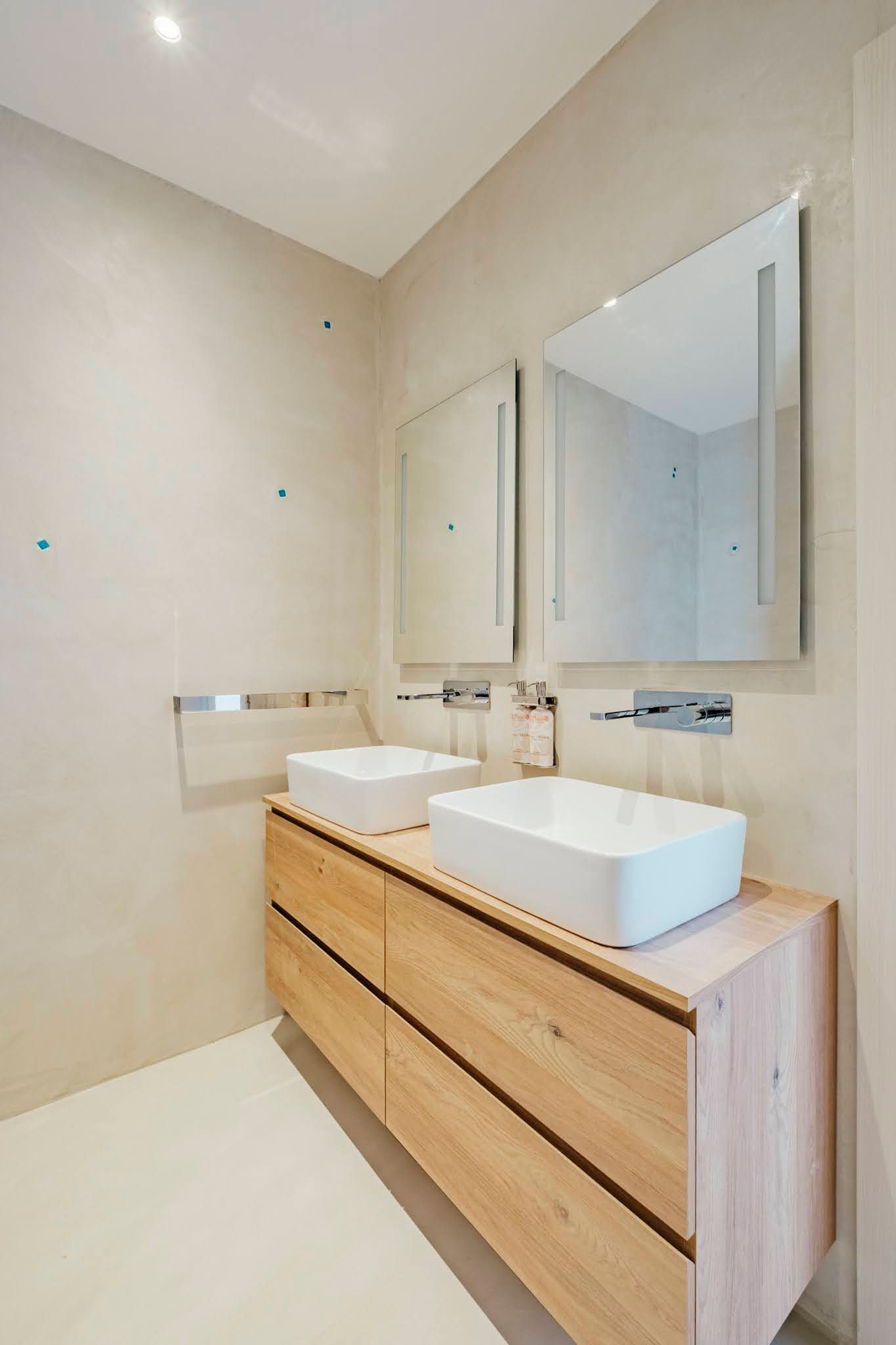 Modern bathroom with a bathtub, two sinks, and a sliding glass door leading to a patio.