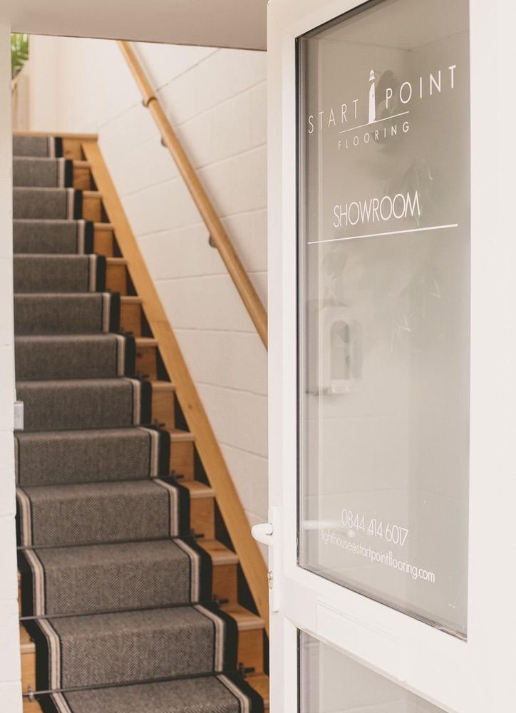 Entrance to flooring showroom, showing monochrome stair runner on wooden stairs