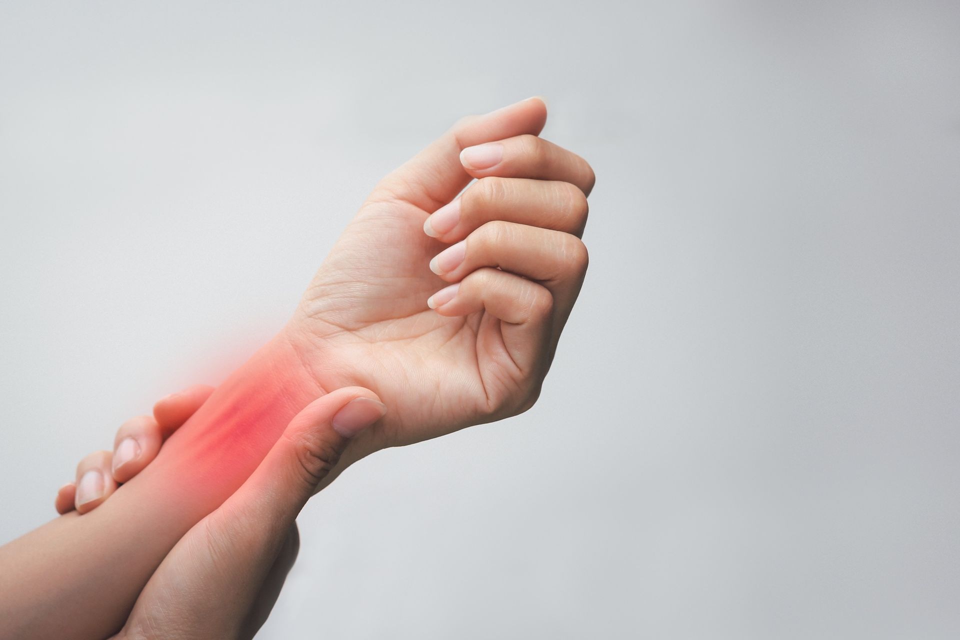 A close-up of a hand clutching the opposite wrist, which is highlighted with a red glow to indicate pain.