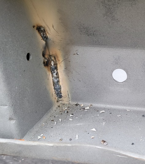 Welded metal corner joint, with visible weld beads and spatter.